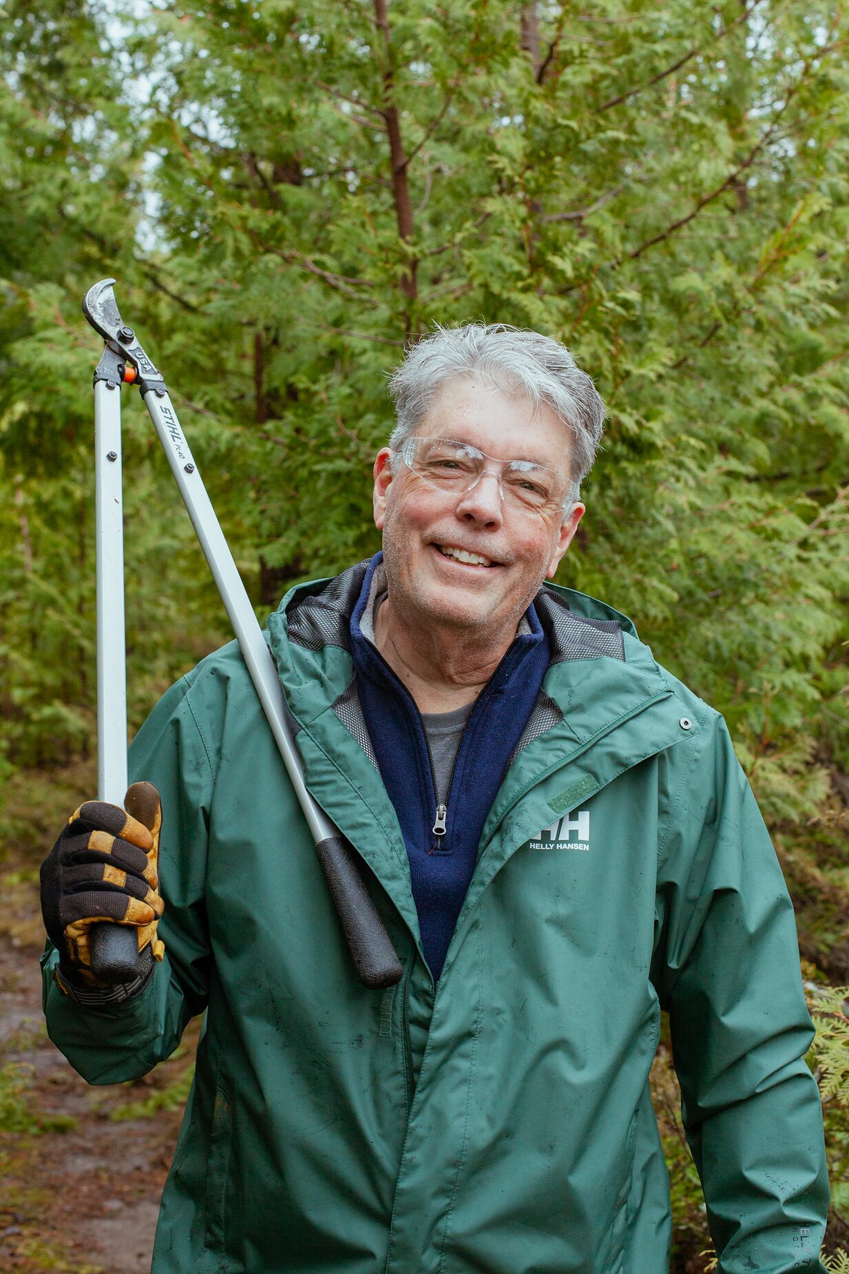 A volunteer carrying loppers over one shoulder after clearing brush at an Anderson Pond workday