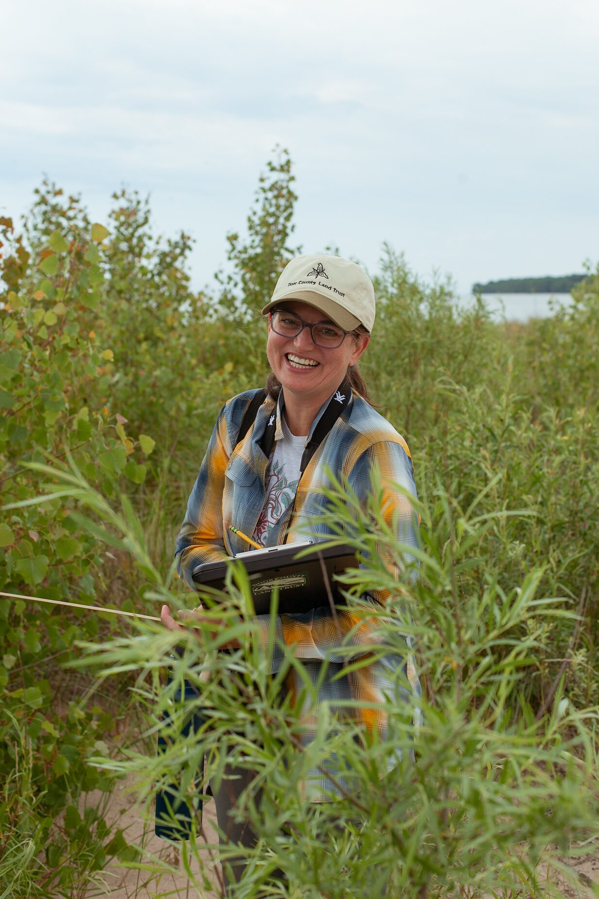 A staffer recording pollinator observations on a tablet in a summer meadow