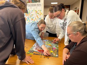 Door County Land Trust staff gathered around the lunch table working together on finishing a bird themed puzzle