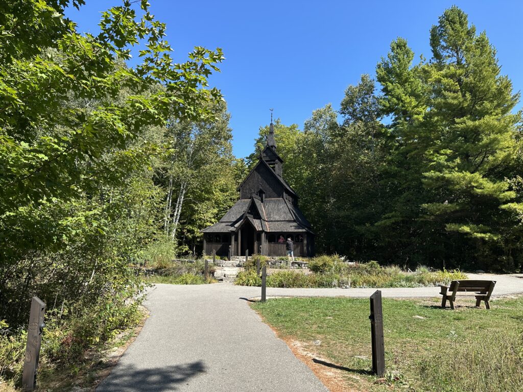 a humble but beautiful church stands in the forest. it's construction is reminiscent of viking style, based on a Norwegian church